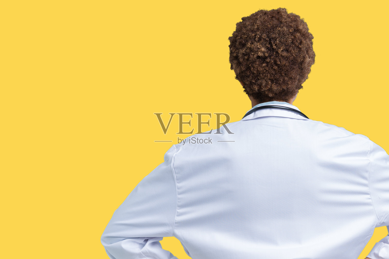 年轻的非洲裔美国医生女人穿医疗外套在孤立的背景站向后看离开与手臂在身体上照片摄影图片