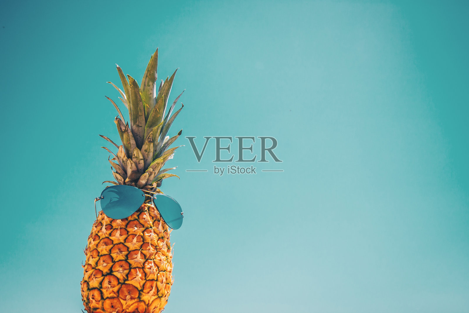 背景与图片的菠萝在太阳眼镜对蓝色的天空-概念照片摄影图片