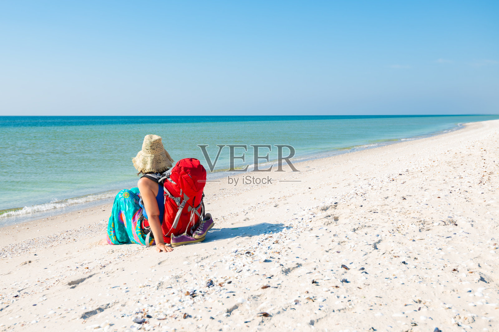 女人在一个pareo与背包放松在荒芜的海滩照片摄影图片