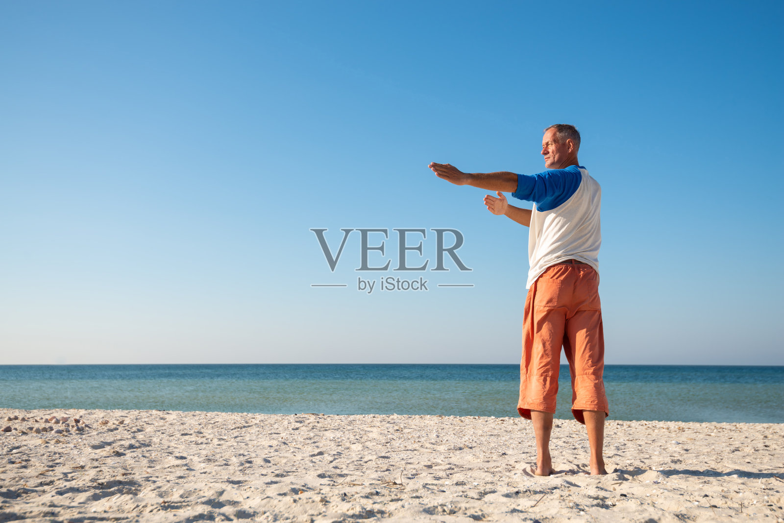 男人站在海滩上练瑜伽照片摄影图片