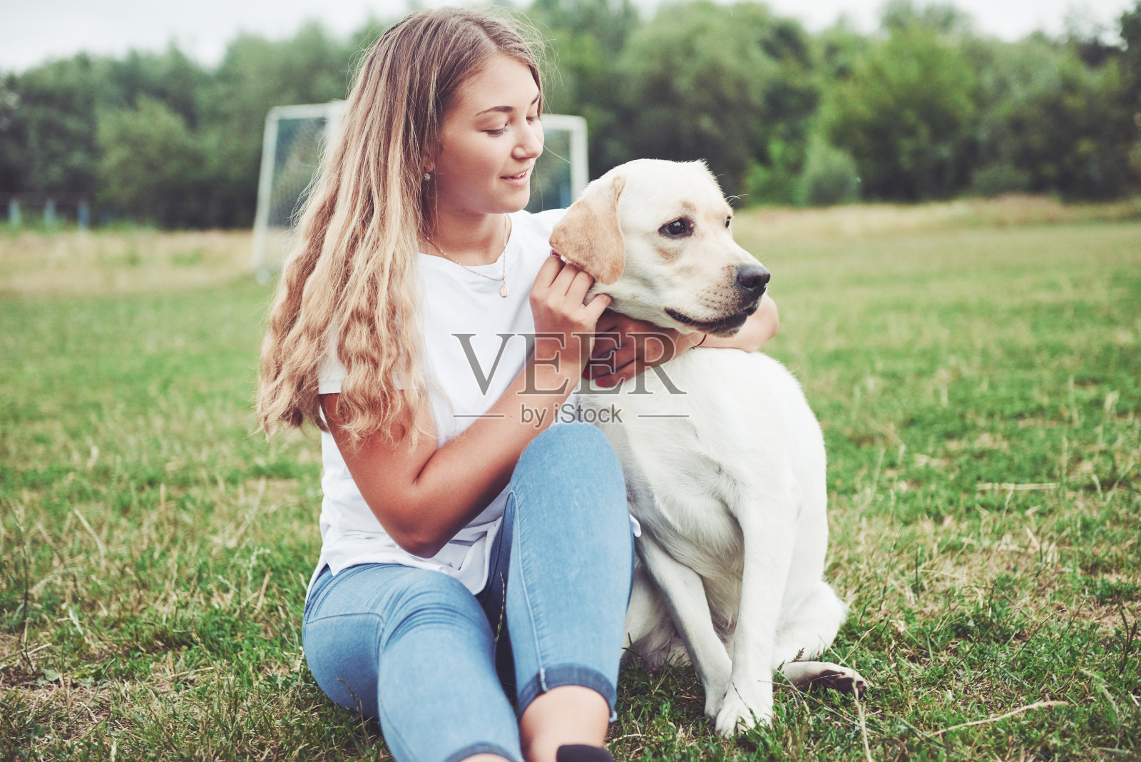 一个漂亮的女孩和一条漂亮的狗在公园的绿草地上。照片摄影图片