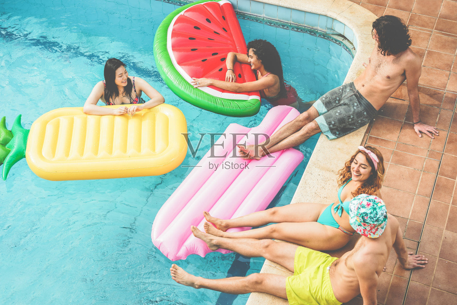 快乐的朋友漂浮与气垫球在游泳池派对-年轻人有乐趣的暑假度假-旅游，友谊，青春和热带概念-集中在水里的女孩照片摄影图片