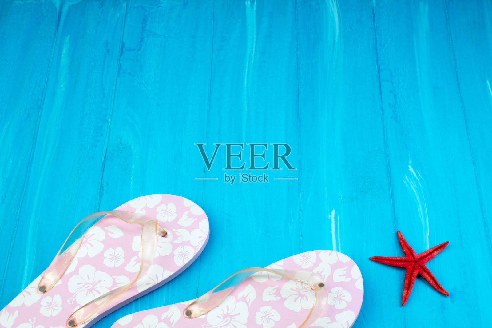 粉色配白花拖鞋沙滩鞋在蓝色的木地板上。俯视图和复制空间。照片摄影图片