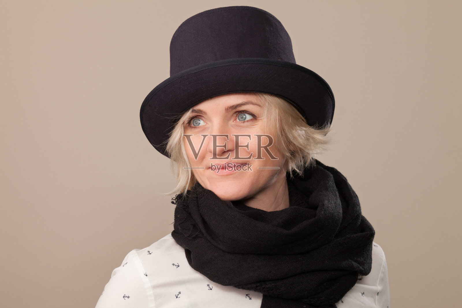 一个迷人的40岁金发女人的工作室肖像在米色的背景上戴着帽子和黑色围巾照片摄影图片