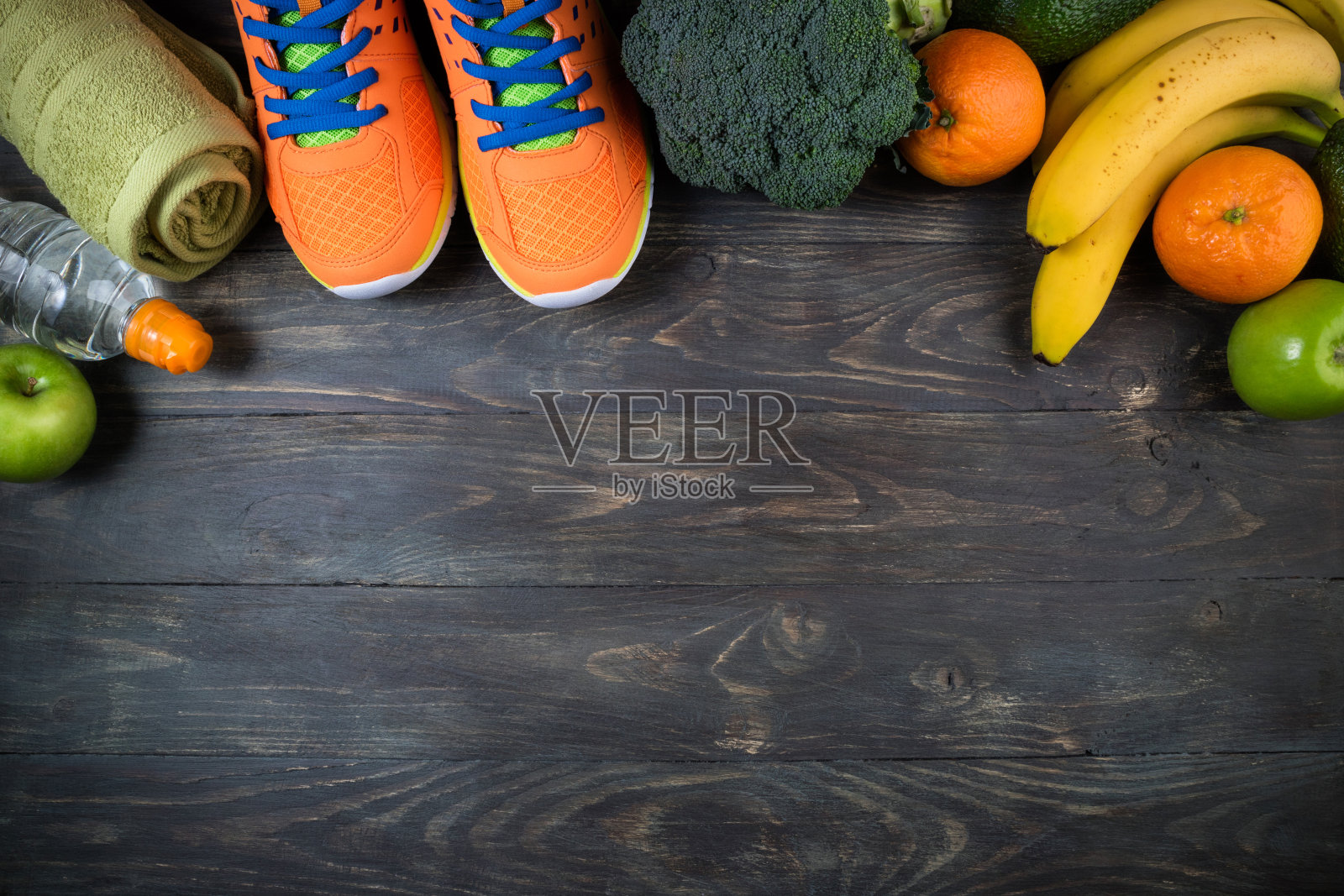运动鞋，瓶装水，水果和蔬菜在木制的背景。成套运动器材和健康食品。健康生活方式、运动和饮食的概念照片摄影图片