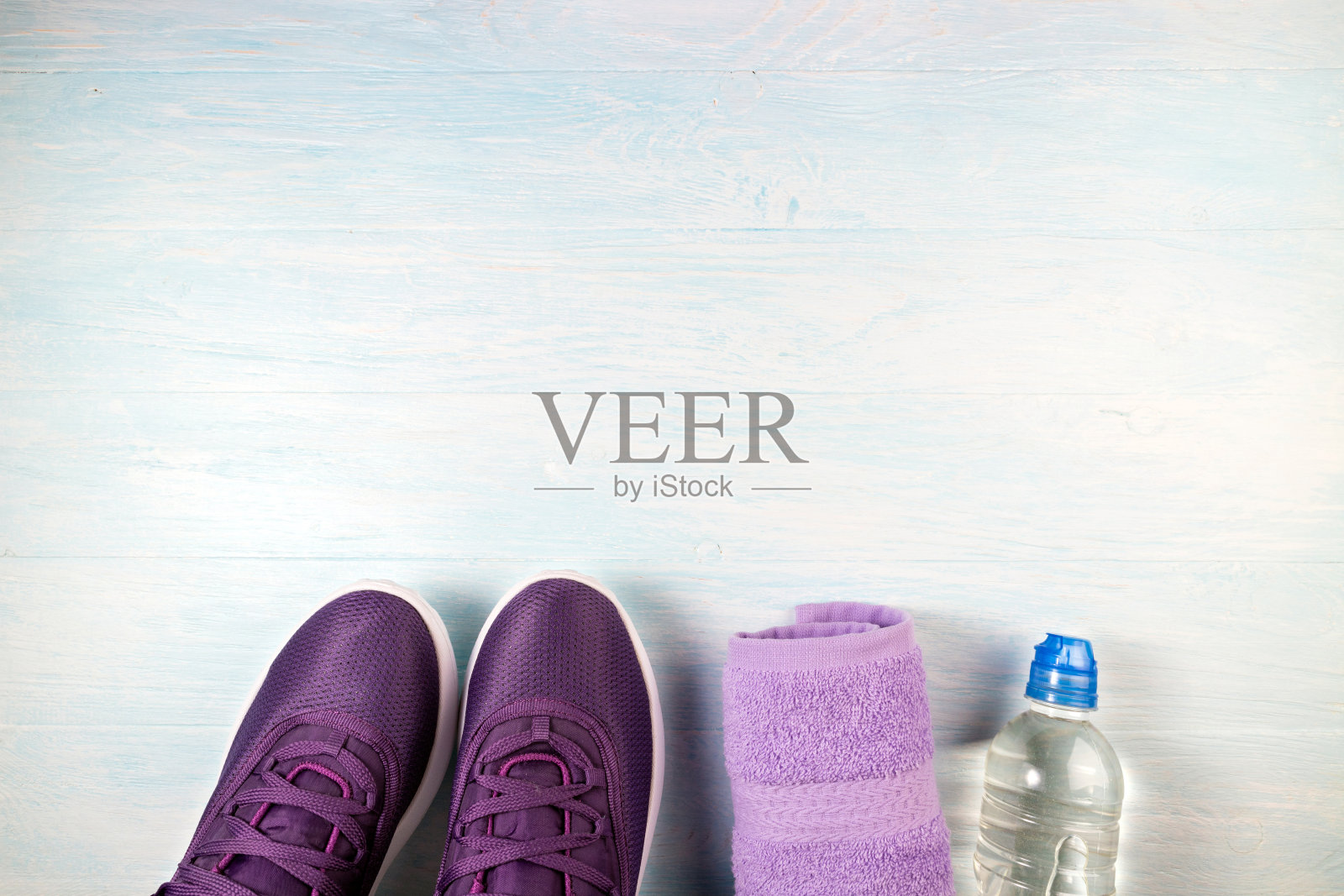 蓝色木质背景上的运动鞋、一瓶水和毛巾。运动设备。健康生活方式、运动和饮食的概念。俯视图照片摄影图片