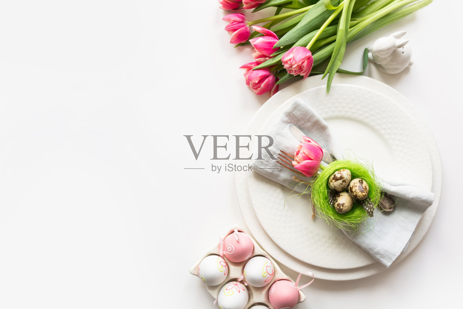 复活节餐桌上白色餐桌上点缀着粉色郁金香。春天的浪漫晚餐。顶部视图和文本空间。照片摄影图片