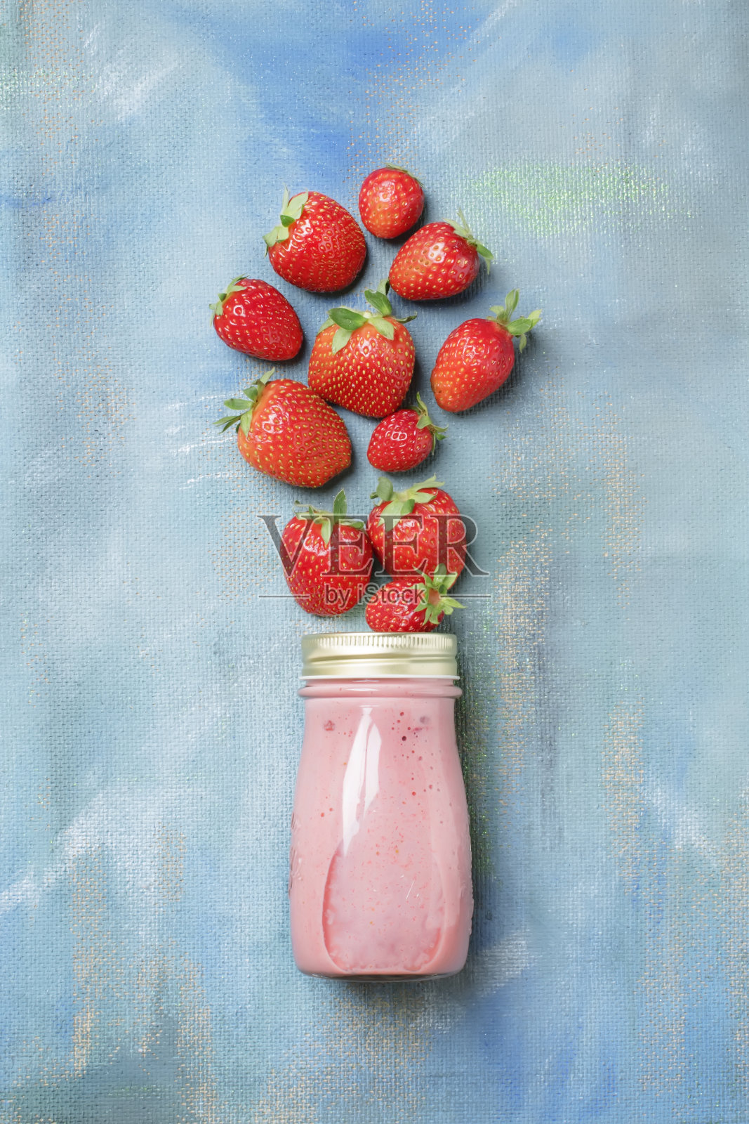 草莓非乳制品冰沙与坚果牛奶在瓶子上的蓝色背景，食物和饮料背景，平铺照片摄影图片