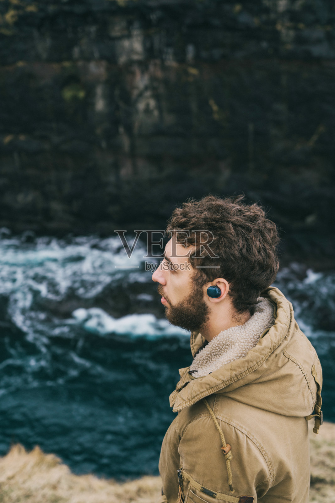 一名戴着无线耳机的男子站在法罗群岛的海边照片摄影图片