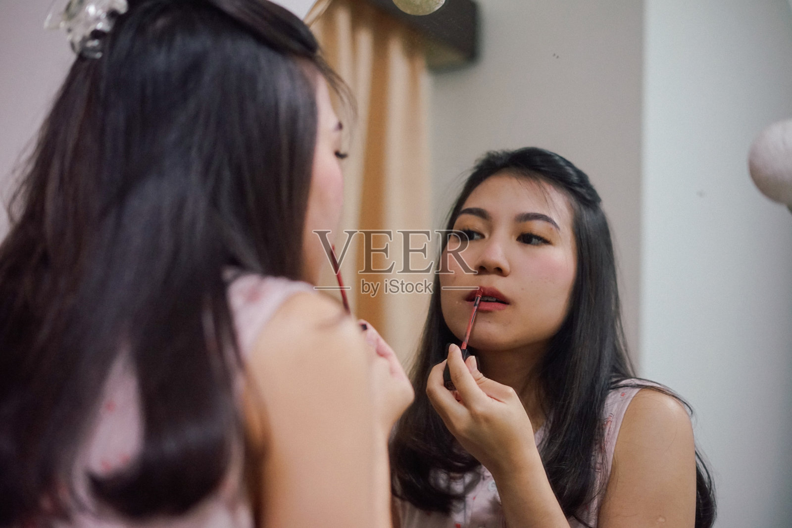 一位年轻的亚洲妇女正在用口红照片摄影图片