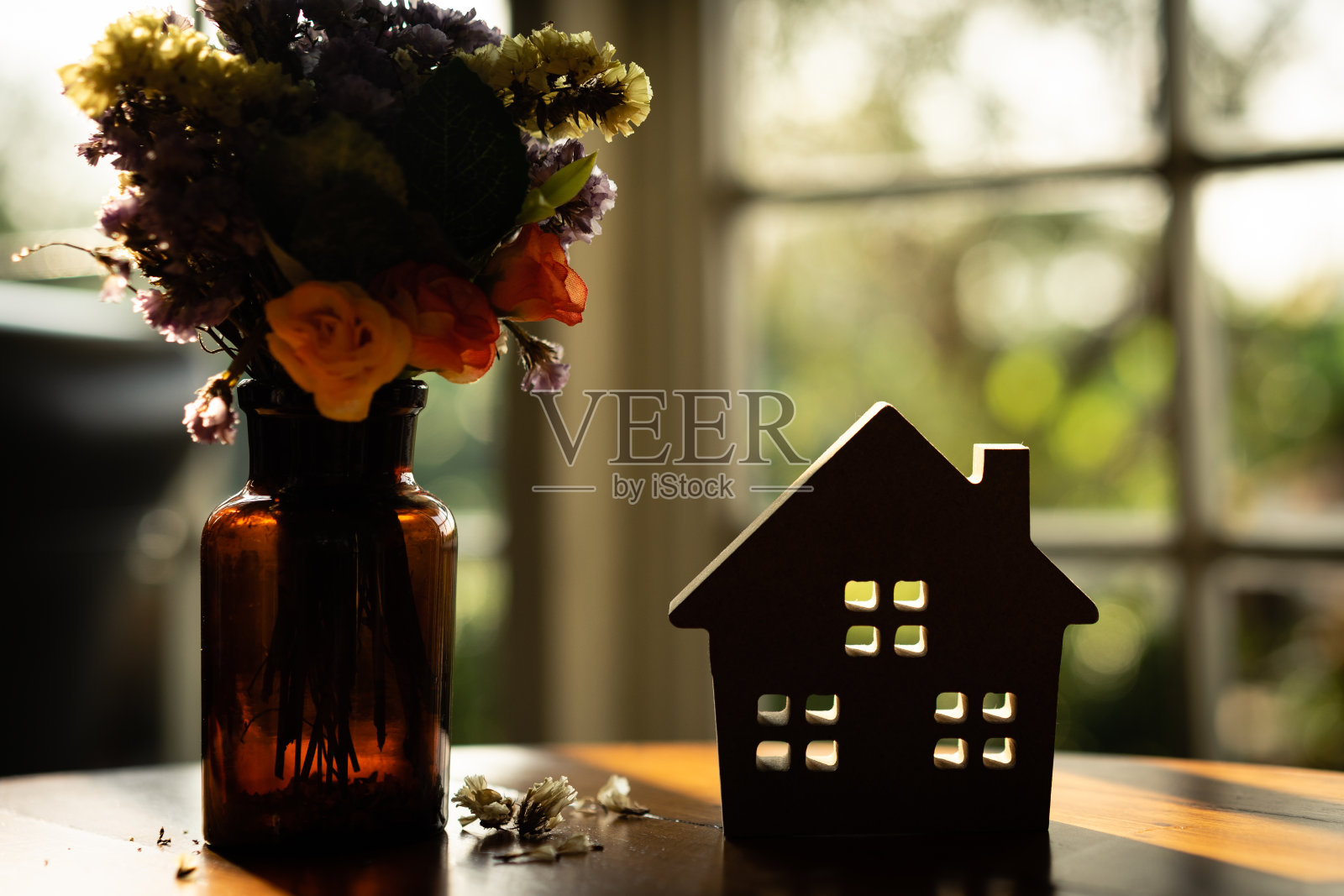 木桌上的干花是硬纸房子的剪影，象征着建筑、生态、贷款、抵押、财产或家庭。照片摄影图片
