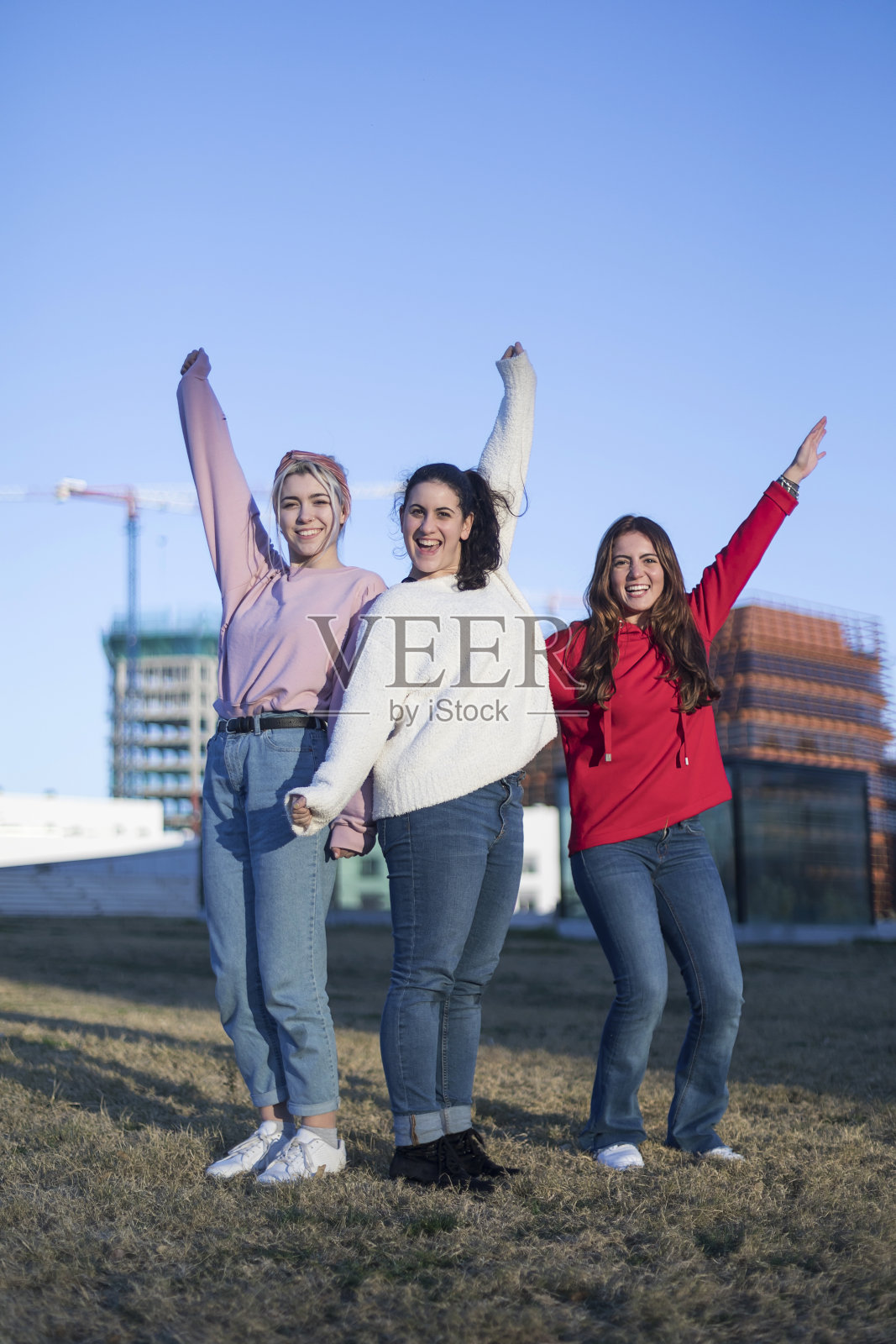 三个快乐的少女朋友在夏季户外的蓝天上跳高照片摄影图片