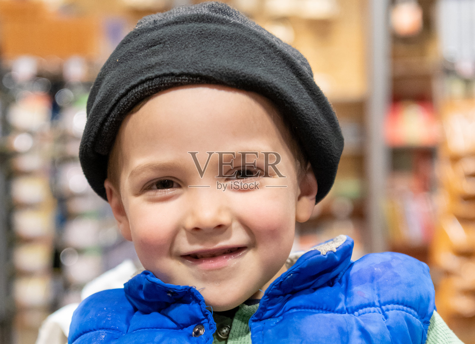 微笑的三岁小男孩坐在超市过道的购物车里照片摄影图片