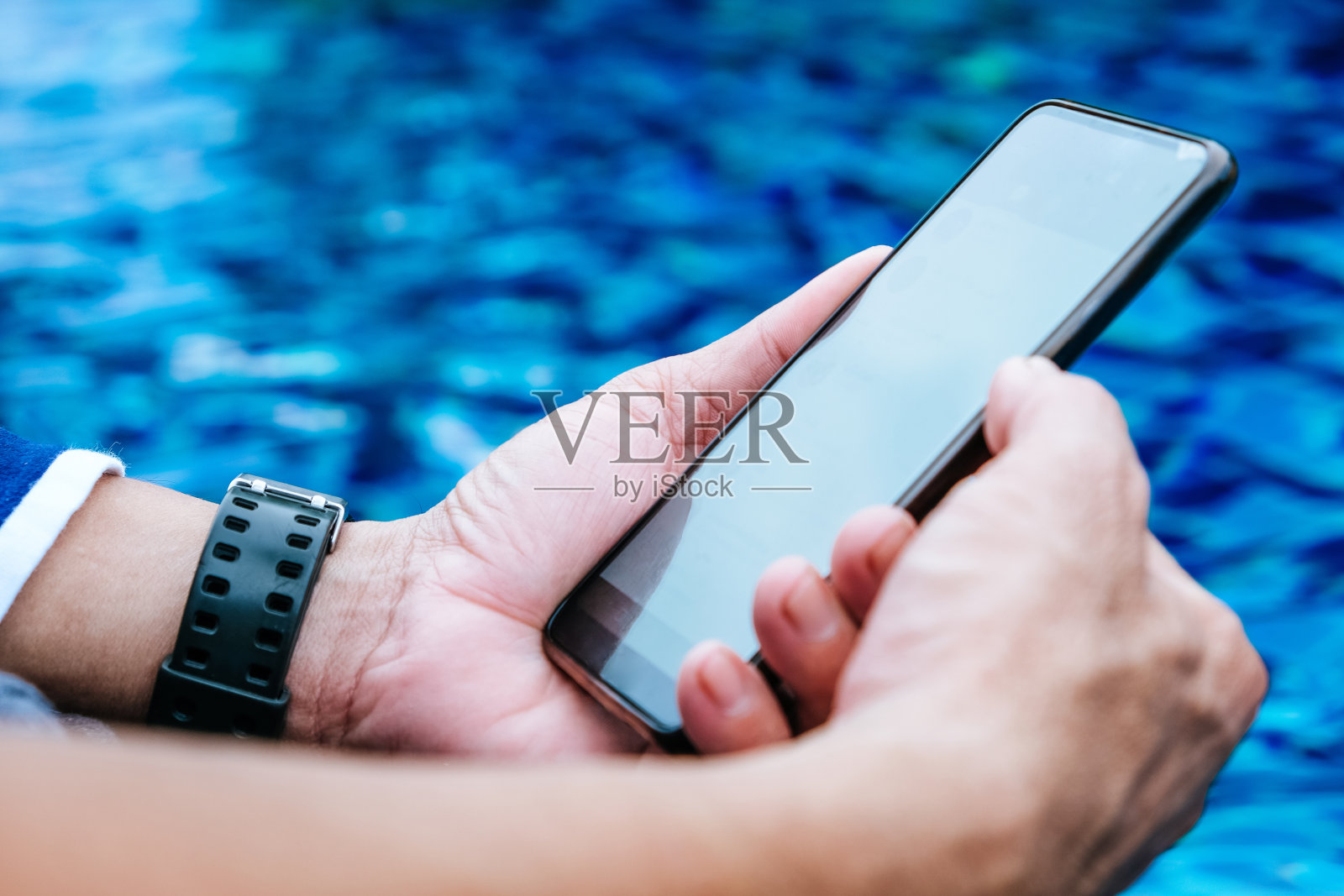 在泳池边用智能手机的男人照片摄影图片