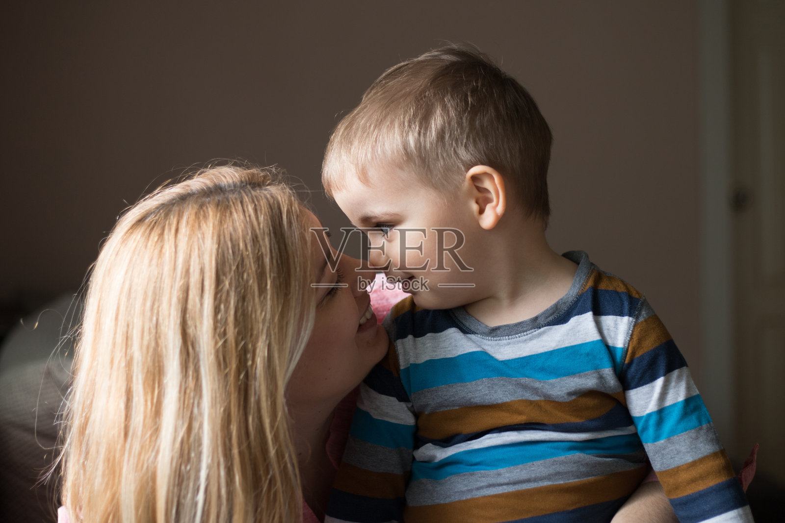 漂亮的女人和她可爱的儿子正摸着鼻子微笑着照片摄影图片