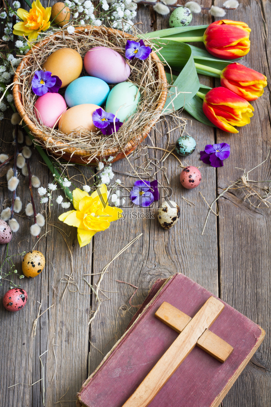 复活节彩蛋在巢与花在古老的木板圣经和十字架照片摄影图片