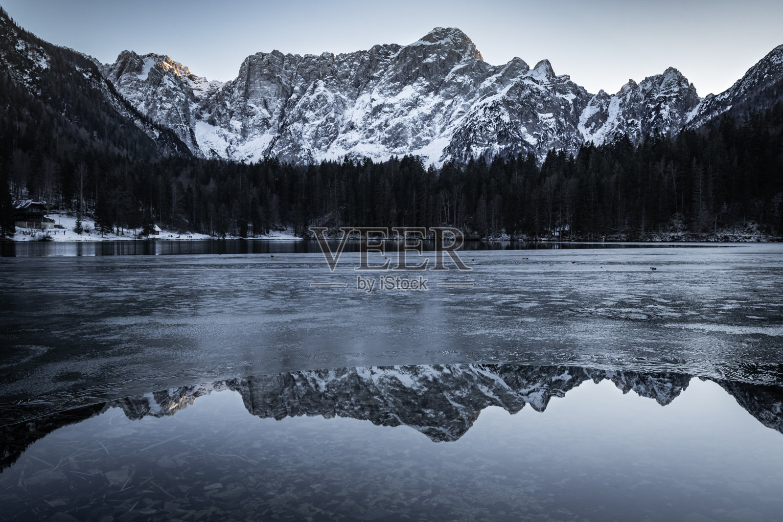 美丽的半冻结的fusine湖在朱利安阿尔卑斯与镜子山反射，意大利照片摄影图片