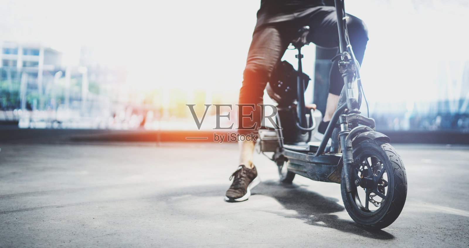 电动城市交通。一个年轻人准备在市中心骑他的电动摩托车。宽照片摄影图片