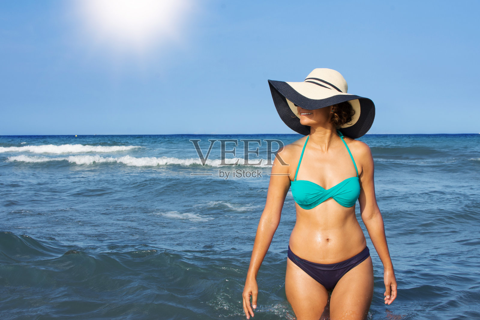 夏天，穿着泳装和太阳帽的年轻女子在海滩上度假。照片摄影图片