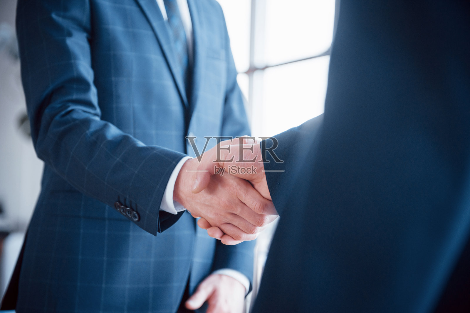 两个自信的商人在办公室开会时握手，成功，交易，问候和合作伙伴的概念照片摄影图片