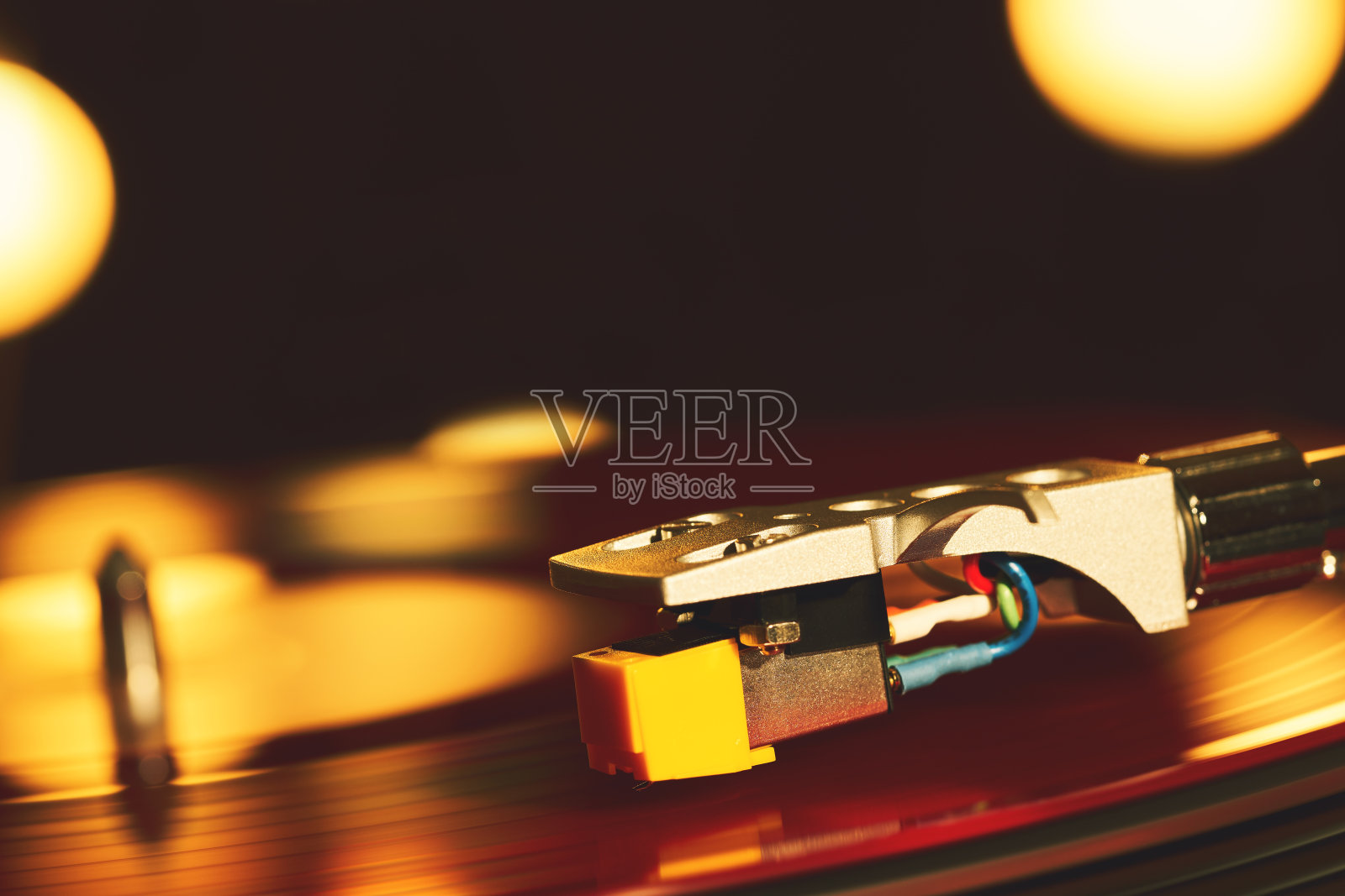 唱片机。音响技术为DJ混合和播放音乐。黑胶唱片上的针。红黑胶唱片。标签。明亮的聚会灯照亮了盘子的表面照片摄影图片