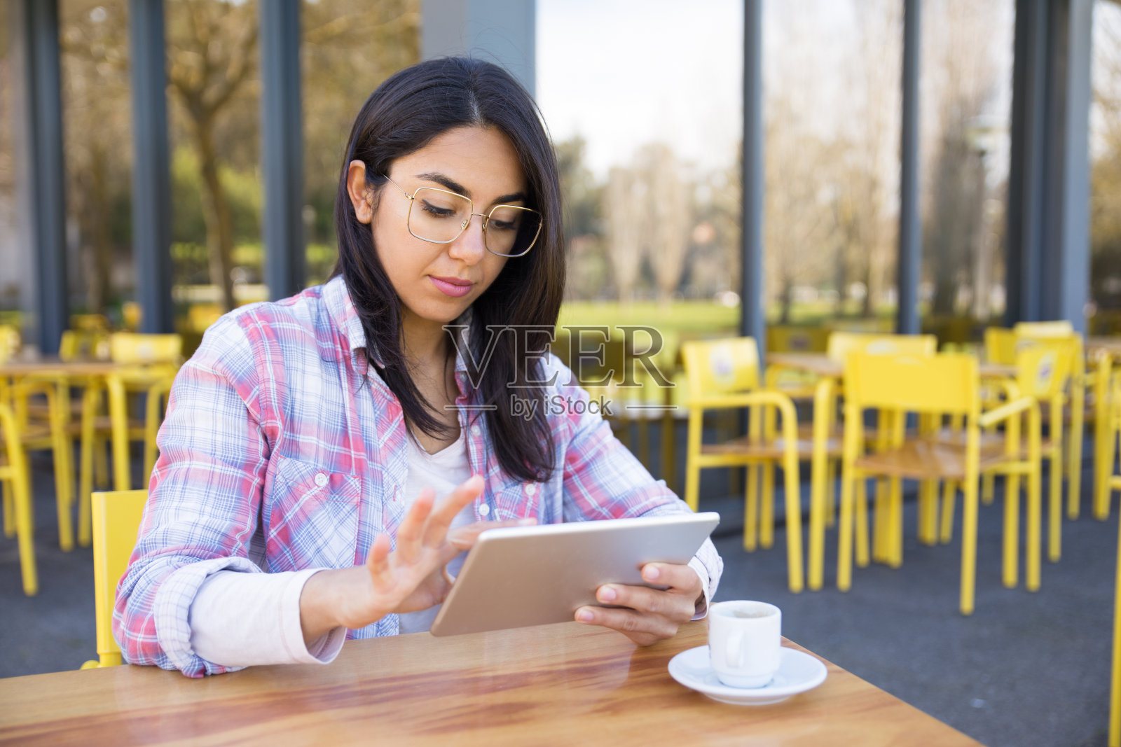严肃的女人用平板电脑，在咖啡馆喝咖啡照片摄影图片