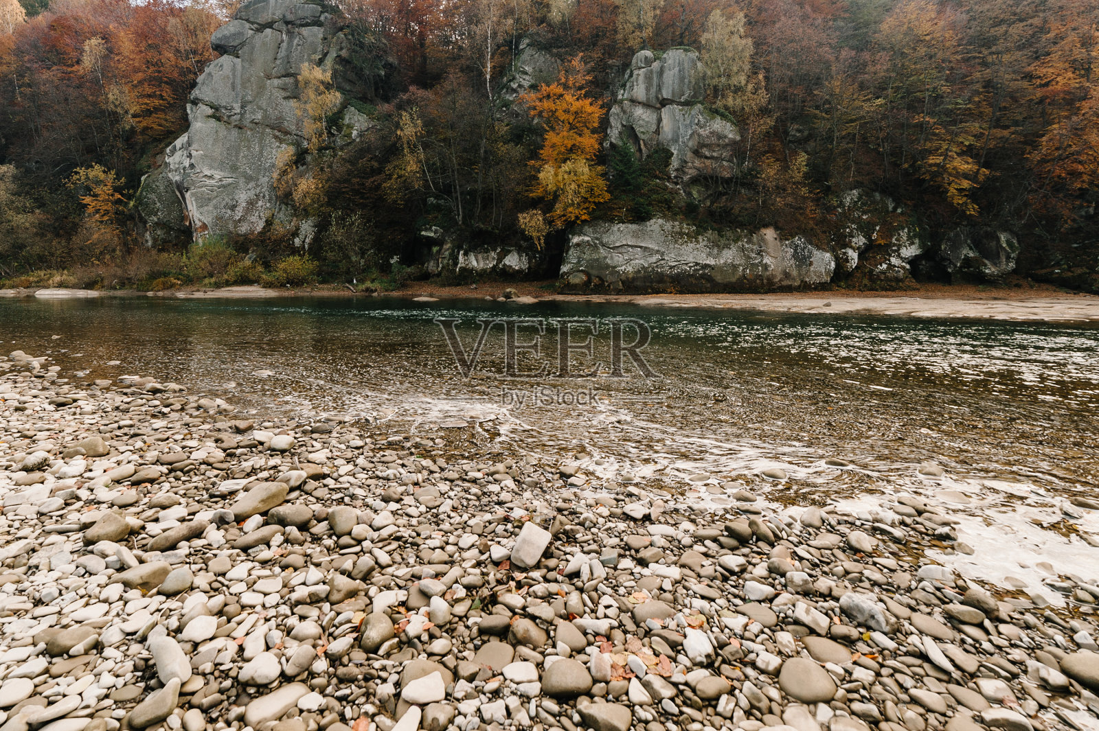 清澈的河流带着岩石通向山脉。
在日落。山上湍急的河水在岩石中流淌着蓝天。景观有森林，河流和石头。山的河。照片摄影图片