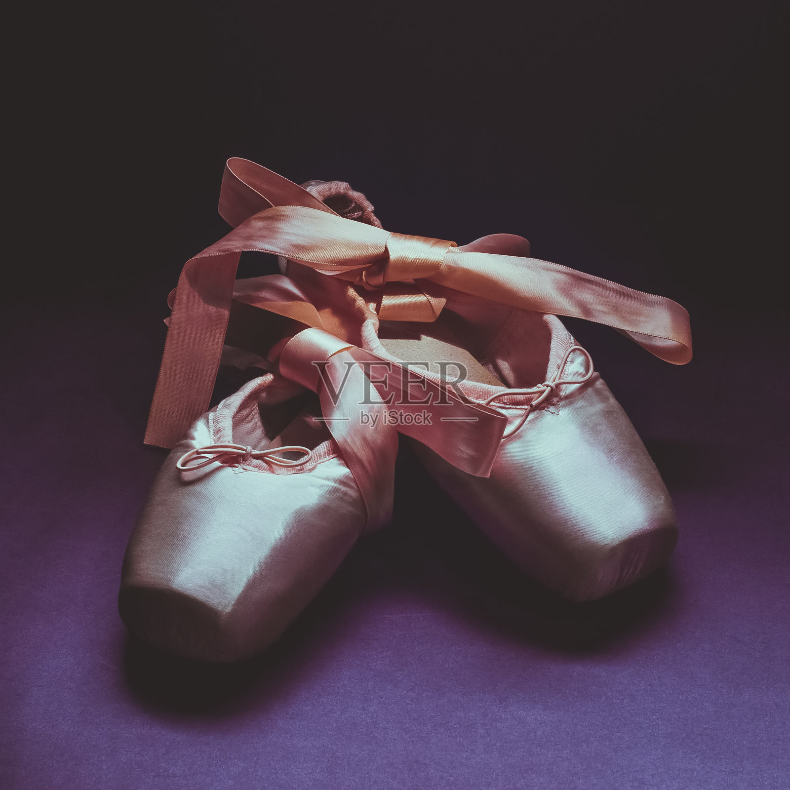 尖头鞋芭蕾舞舞鞋与蝴蝶结的丝带漂亮地折叠在一个黑暗的背景。照片摄影图片