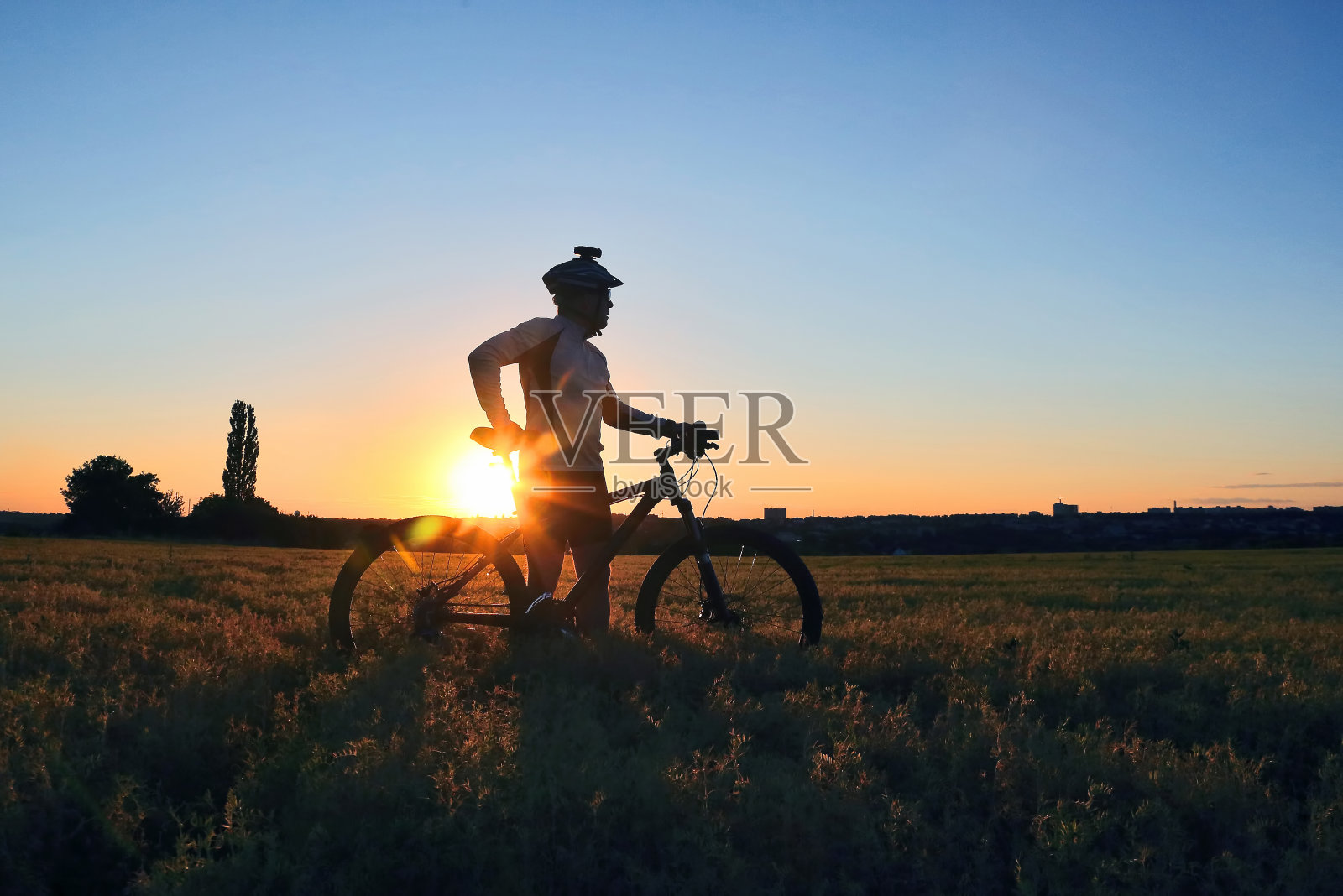 一个骑自行车的人的剪影在日落的田野照片摄影图片