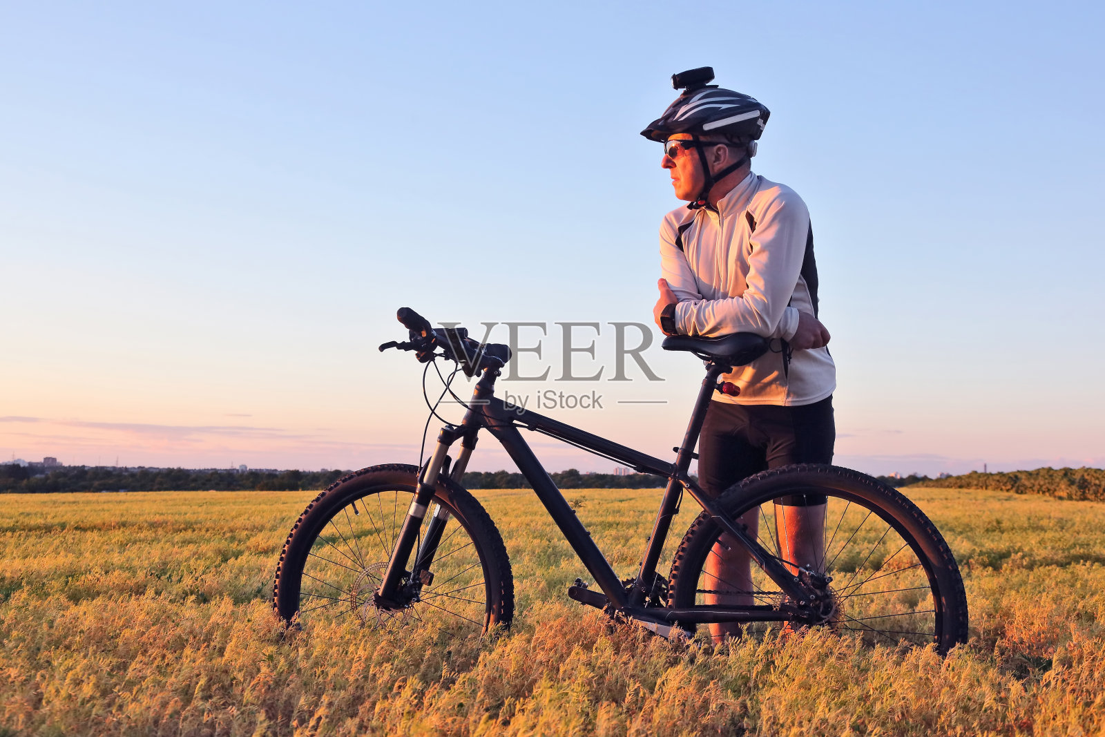 骑着自行车的人在田野里看日落照片摄影图片