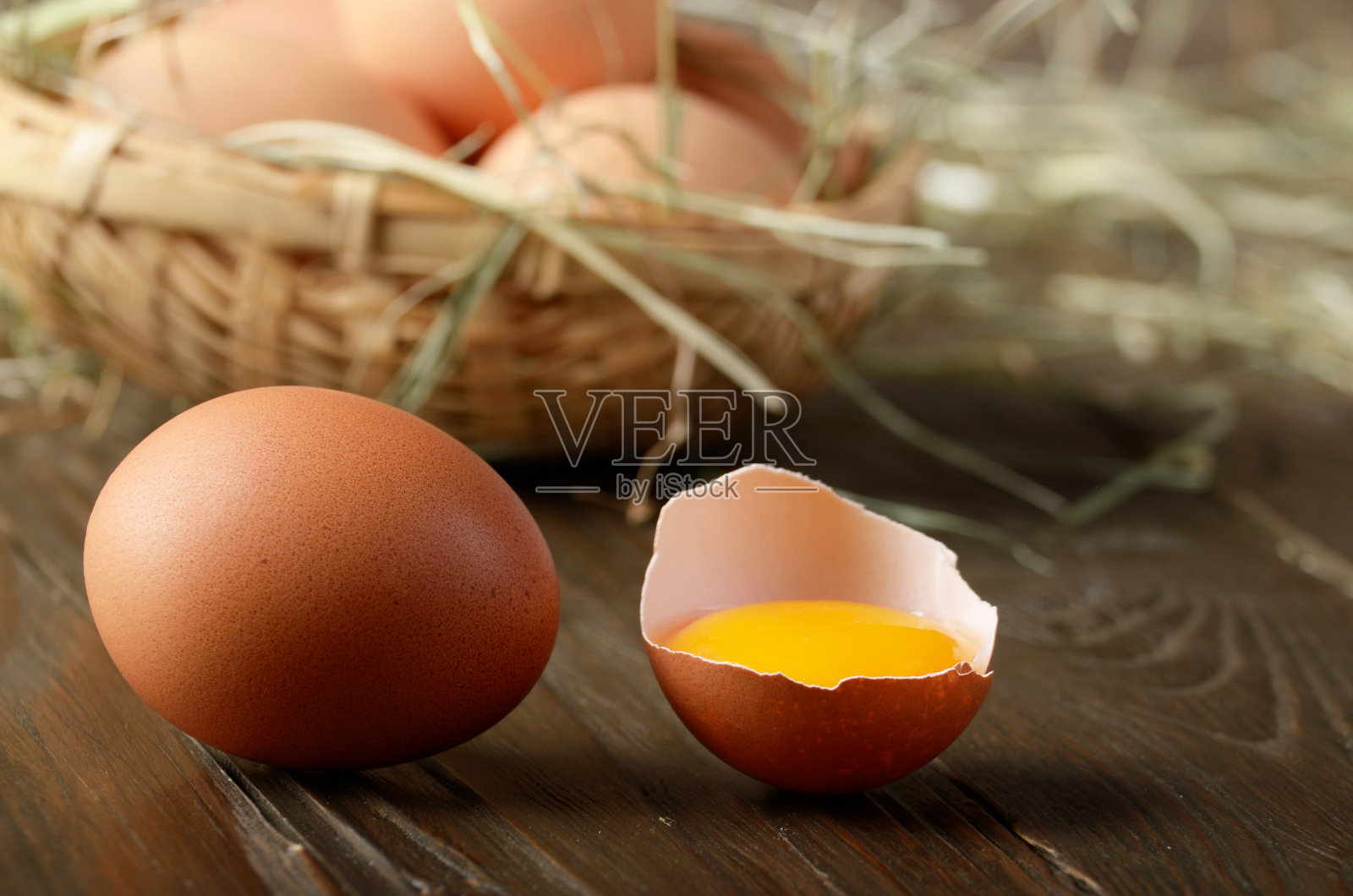 带蛋黄的破鸡蛋和新鲜的棕色有机鸡蛋放在木桌上照片摄影图片