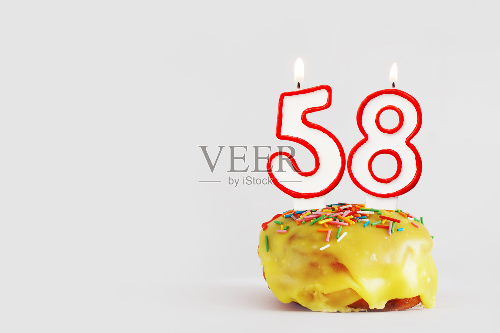 五十八年的纪念日。生日纸杯蛋糕与白色燃烧的蜡烛与红色边框形式的58号。浅灰色背景与复制空间照片摄影图片