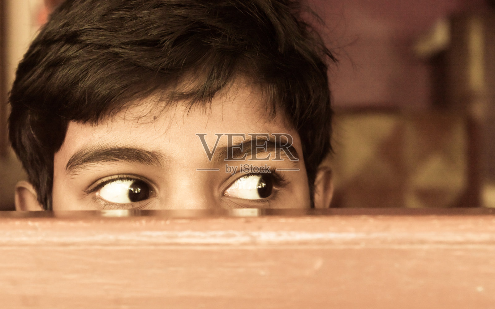小男孩好奇地望着窗外。照片摄影图片