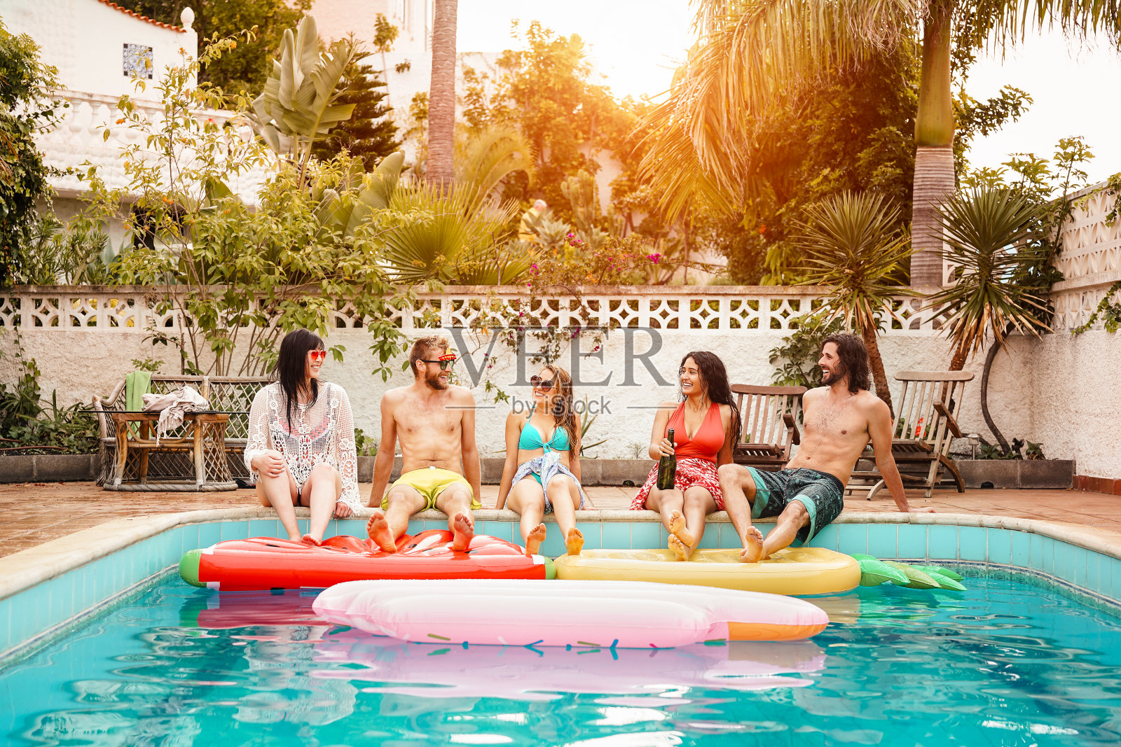 一群快乐的朋友在游泳池放松-年轻人在专属的夏季热带度假-友谊，假期和青年的生活理念照片摄影图片