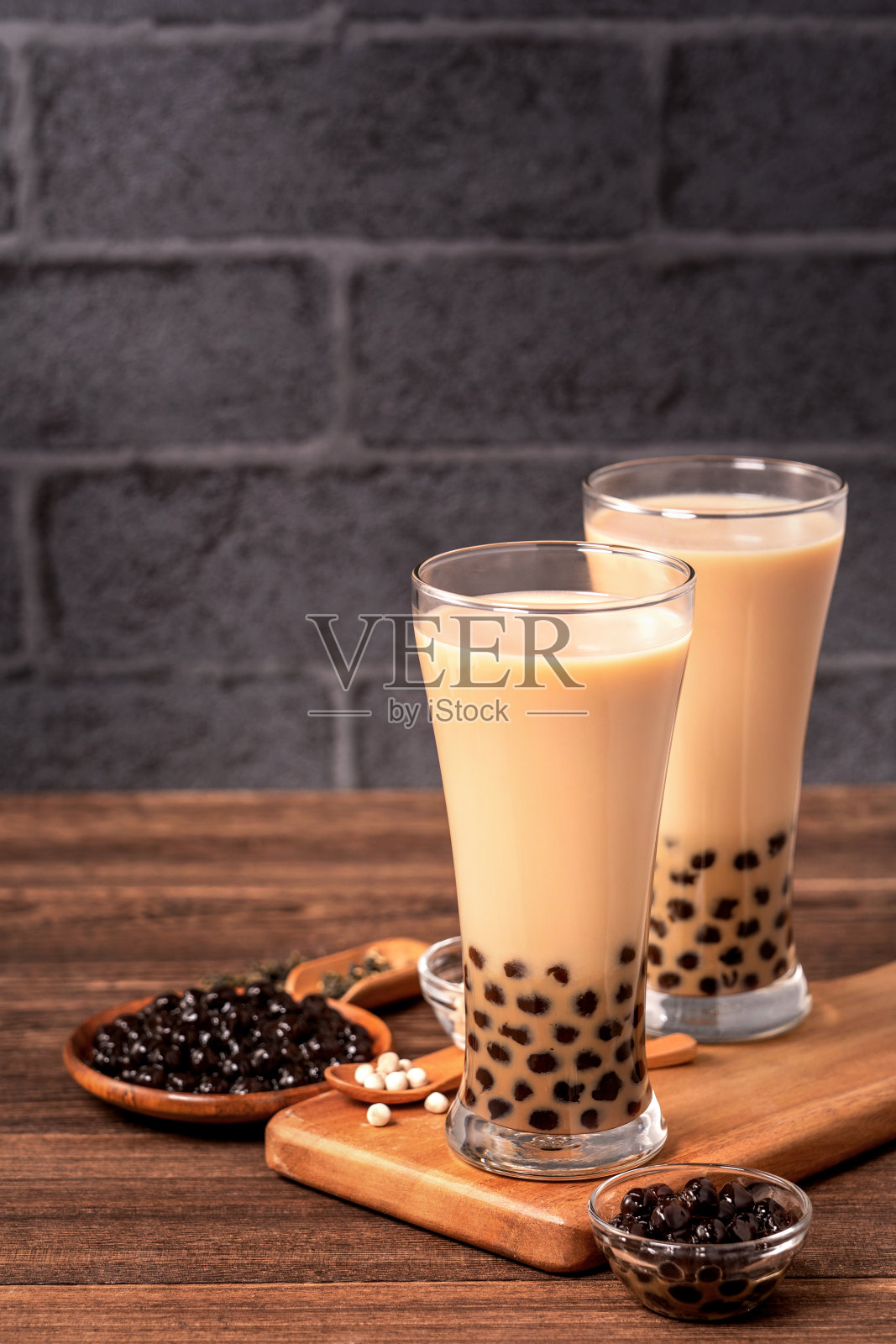美味的珍珠奶茶和珍珠球在玻璃木桌和深灰色的砖背景，台湾流行的食品和饮料，近距离观看照片摄影图片