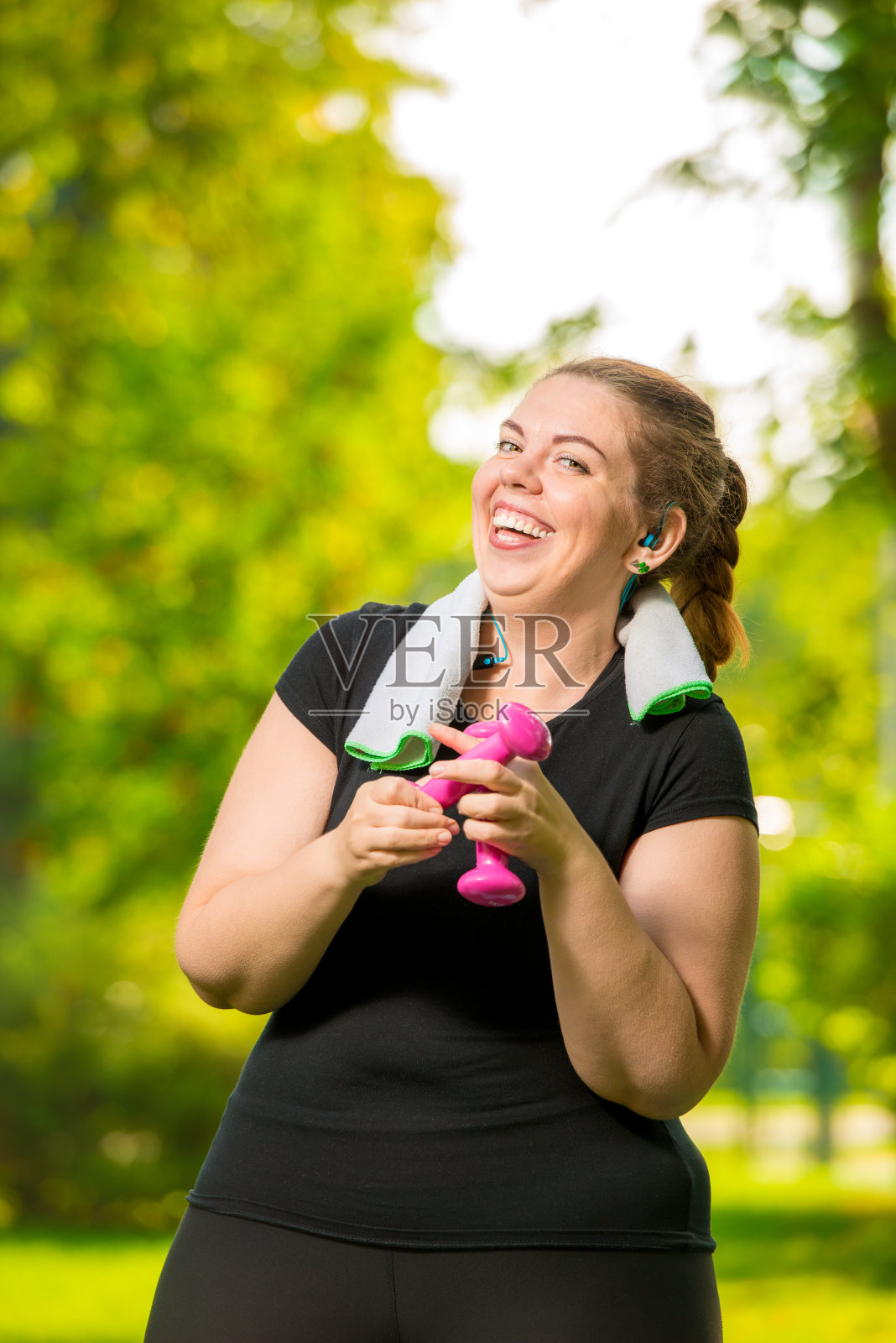 快乐的30岁的女人，大码没有复杂处理哑铃在一个夏天的公园锻炼照片摄影图片