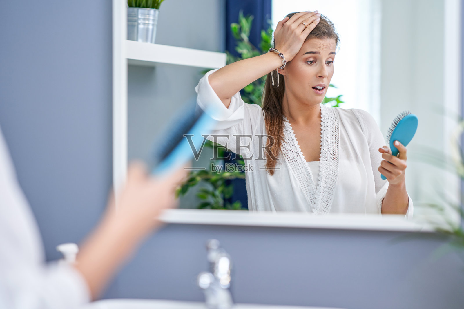 在浴室梳头的快乐女人有脱发的问题照片摄影图片