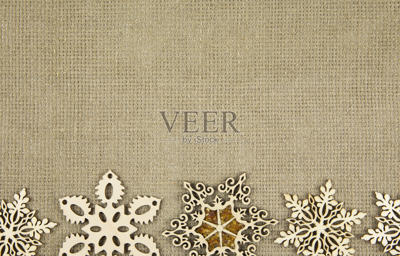 平铺的激光切割木质雪花在粗麻布纺织品上，圣诞背景。插画图片素材