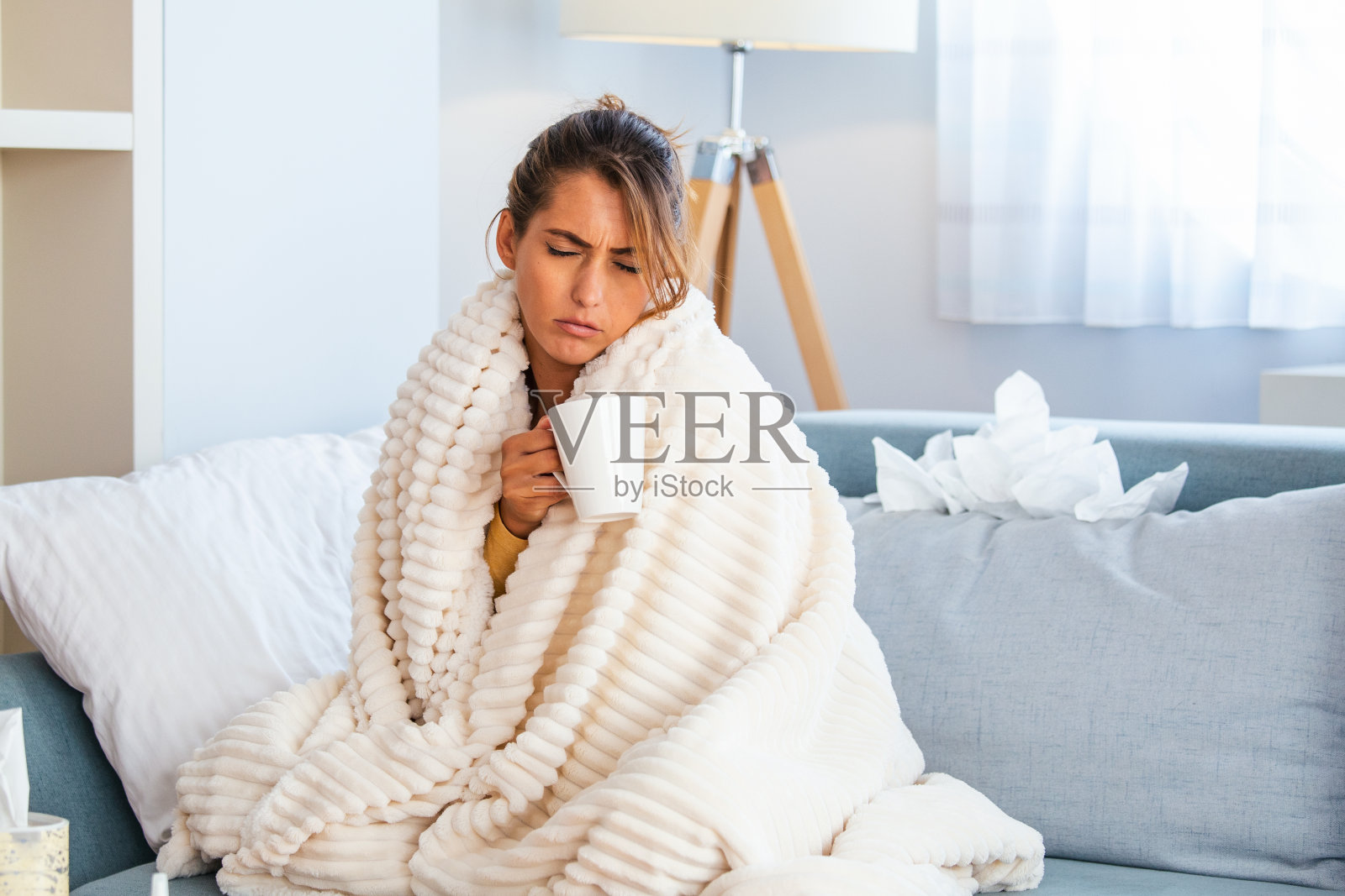 感冒和流感。生病的女人的肖像感冒，生病和打喷嚏在纸擦。特写美丽的不健康的女孩覆盖在毯子擦拭鼻子。医疗保健的概念。照片摄影图片