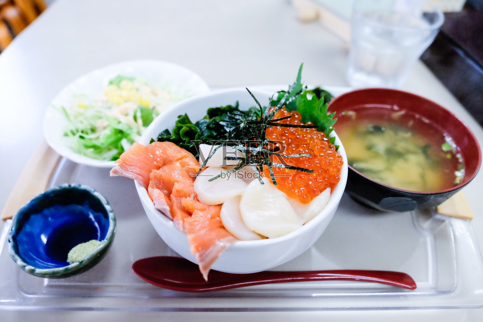 生鱼片套餐米饭，混合生鱼片，生鲑鱼，贝壳，鲑鱼蛋，海藻，与味噌汤，芥末，蔬菜，勺子，日本食物被称为Kaisen don或Ikura don。照片摄影图片