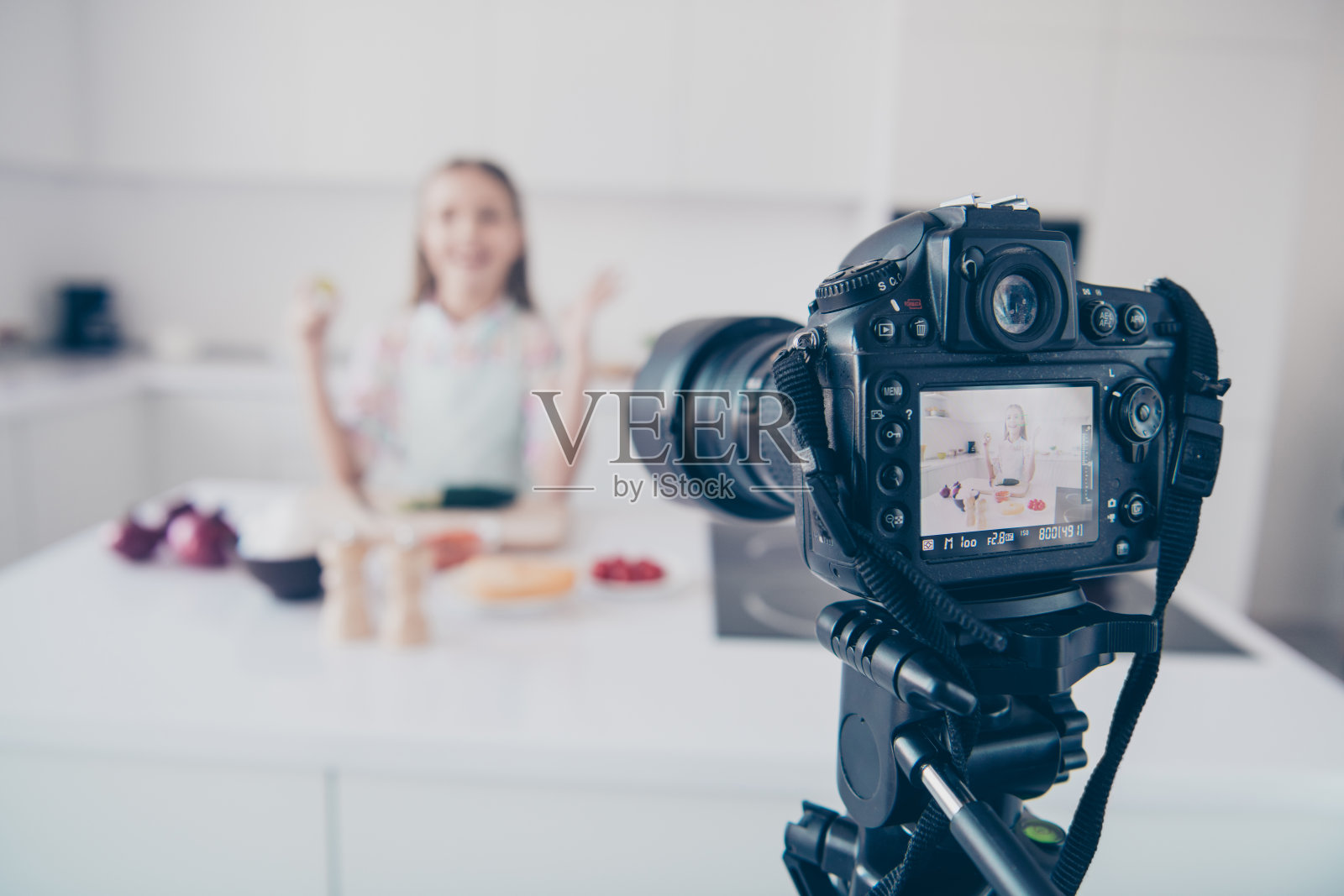 专业摄像机录制视频课的特写，吸引人的，美丽的，愉快的，愉快的，十几岁的女孩在浅色的室内厨房房子室内做有用的维生素蔬菜沙拉菜照片摄影图片