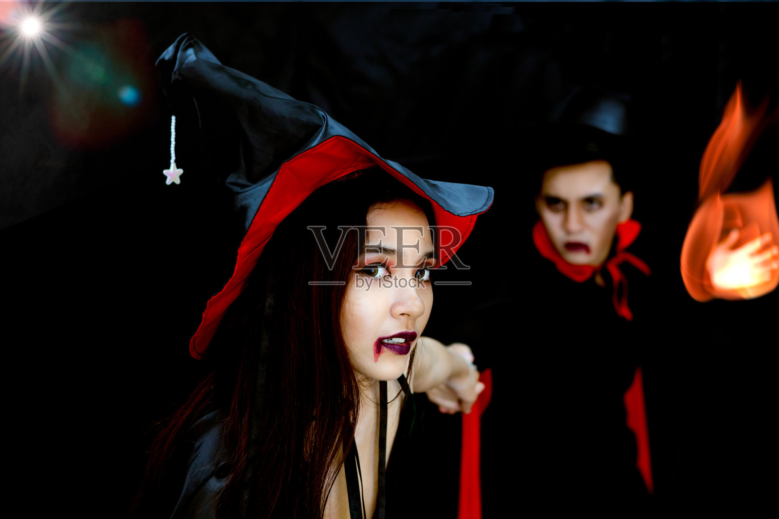 巫师与火手拉女巫女人在黑暗的背景和镜头光晕在万圣节派对照片摄影图片