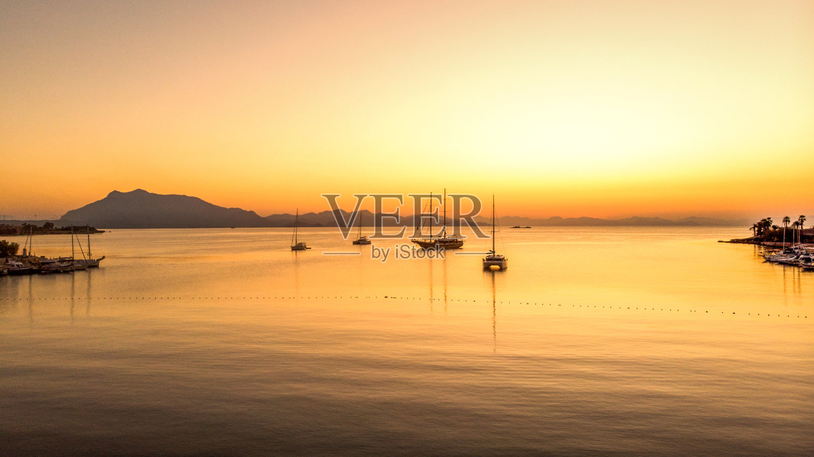 鸟瞰图Datça镇和港口和帆船在日出。照片摄影图片