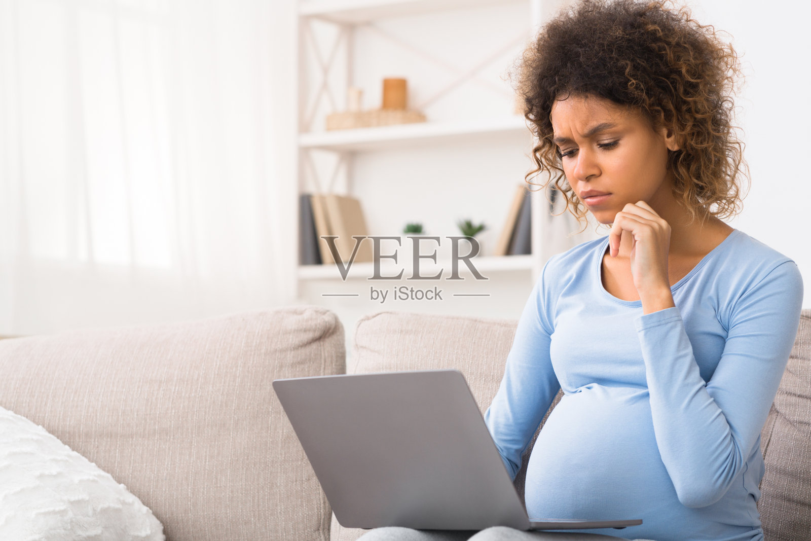沉思的孕妇在家里使用笔记本电脑照片摄影图片