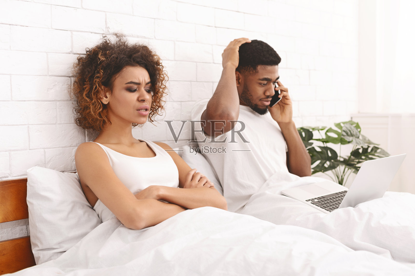 被冒犯的非洲妻子躺在床上和她打电话的丈夫照片摄影图片