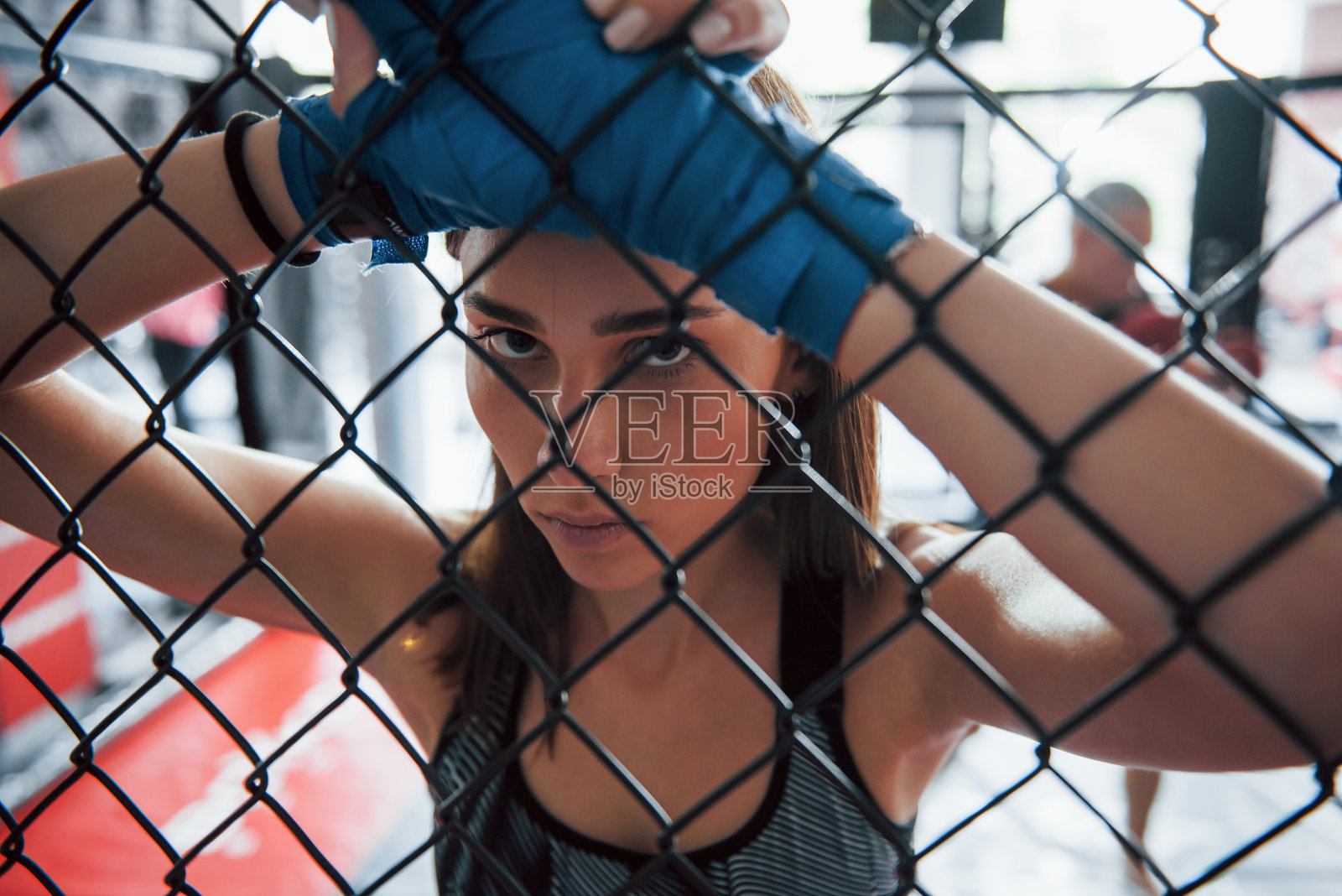 休息。女运动员在拳击台上锻炼身体。靠在篱笆上照片摄影图片