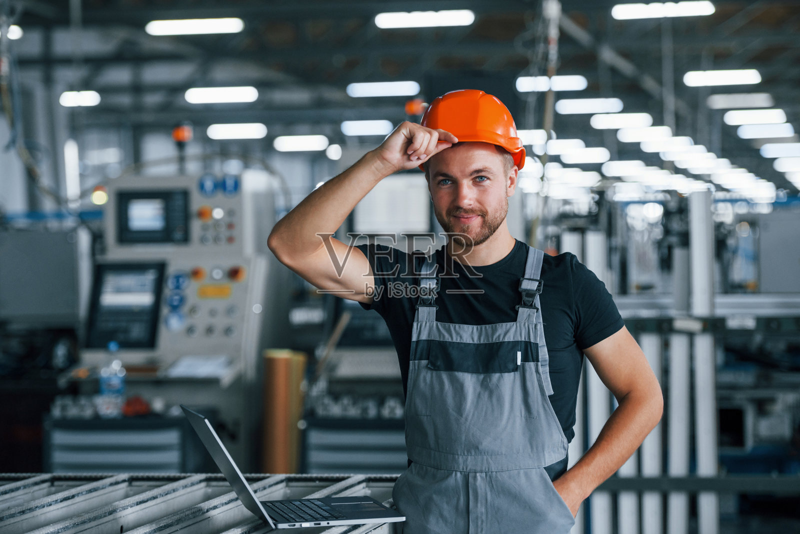 接触防护头盔。工厂内的工业工人。戴着橙色安全帽的年轻技术员照片摄影图片