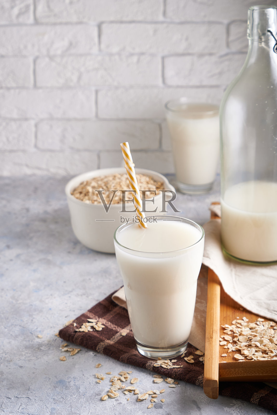 健康的替代牛奶。自制燕麦牛奶在玻璃和瓶子轻桌上不含乳糖照片摄影图片