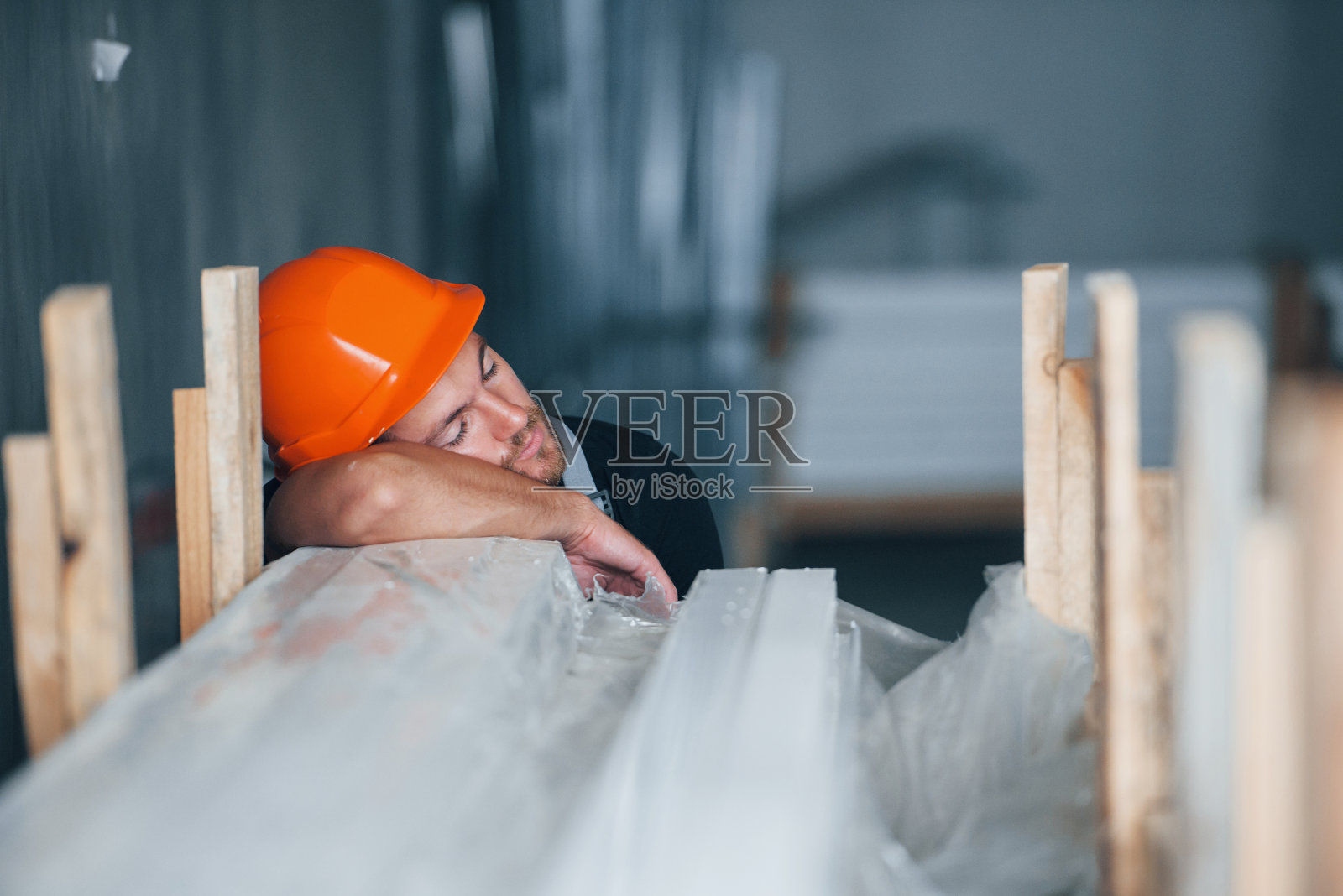 工作时睡觉。休息。工厂内的工业工人。戴着橙色安全帽的年轻技术员照片摄影图片