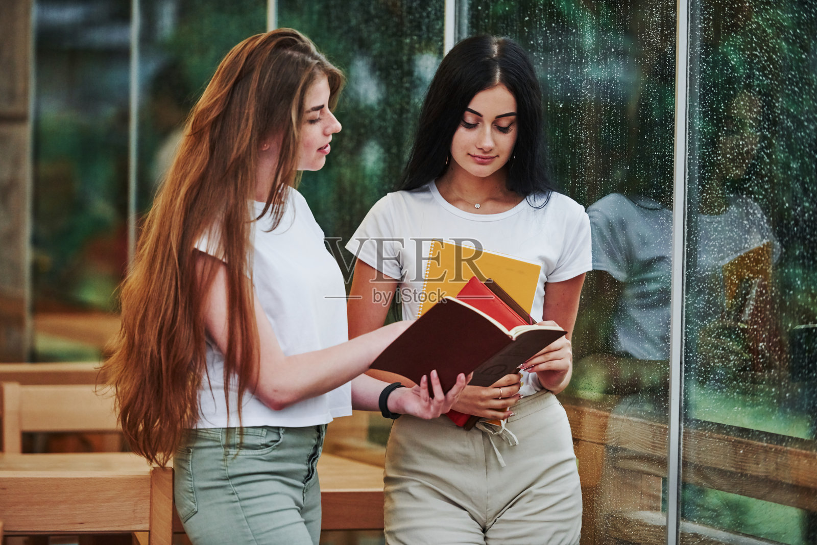 下雨天，两个女学生在咖啡馆里聊天照片摄影图片